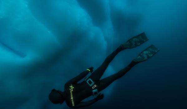 Plongeur en apnée nageant près d'un iceberg