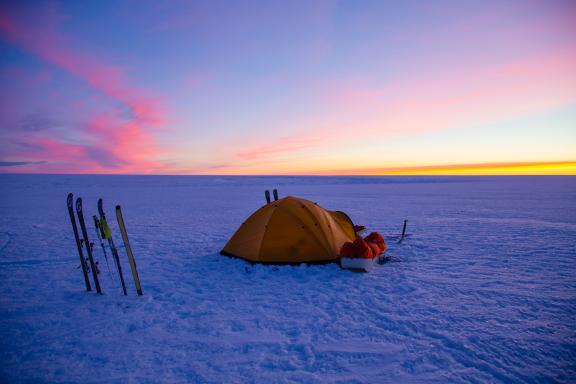 Voyage d'aventure et bivouac avec un coucher de soleil sur la traversée sud-nord du Groenland